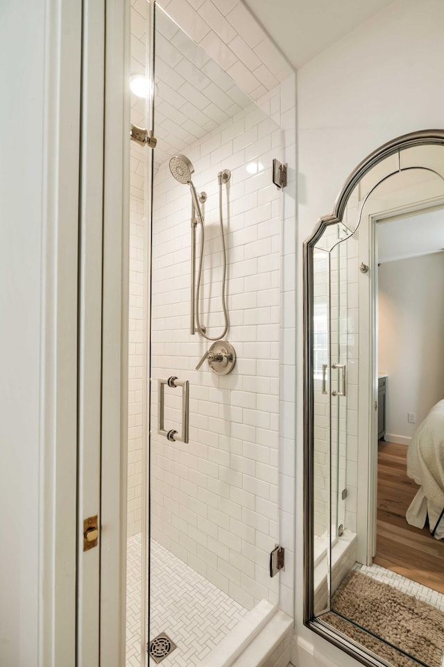 bathroom with connected bathroom, a shower stall, and wood finished floors