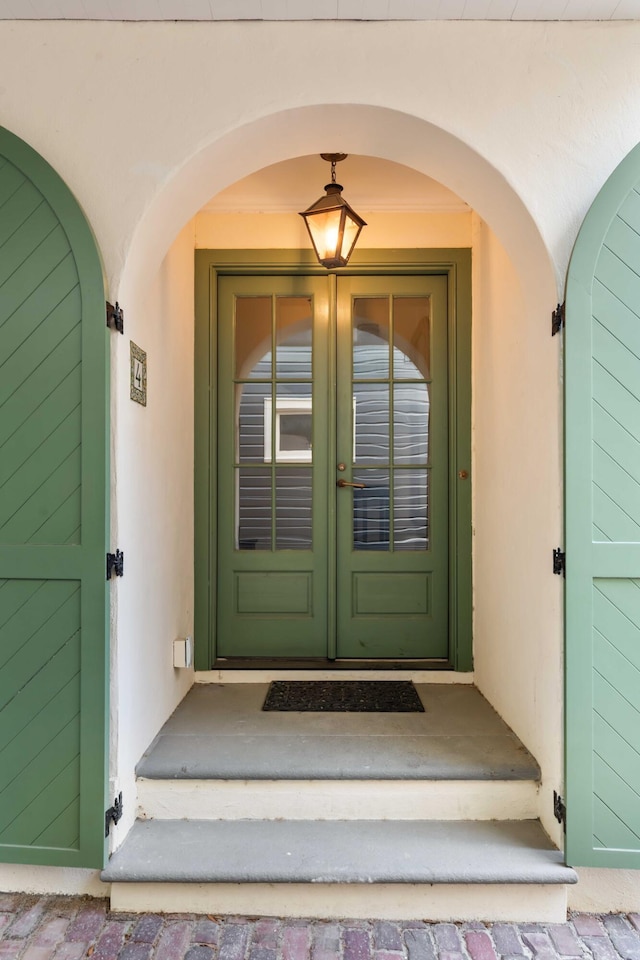view of exterior entry featuring french doors and stucco siding