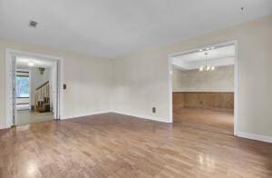 empty room featuring a chandelier and wood-type flooring