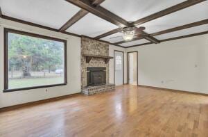 unfurnished living room with wood-type flooring, a wealth of natural light, and a brick fireplace