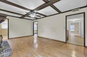 unfurnished living room with beamed ceiling, coffered ceiling, and hardwood / wood-style flooring