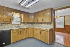 kitchen featuring a chandelier, dishwasher, a healthy amount of sunlight, and wood walls