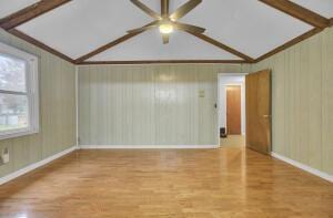 empty room with hardwood / wood-style floors, vaulted ceiling, and ceiling fan