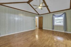 unfurnished room with lofted ceiling with beams, hardwood / wood-style flooring, and ceiling fan