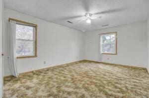 empty room with carpet flooring, a wealth of natural light, and ceiling fan