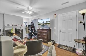 living room featuring a fireplace, wood-type flooring, and ceiling fan