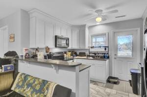 kitchen with a kitchen bar, appliances with stainless steel finishes, kitchen peninsula, and white cabinets