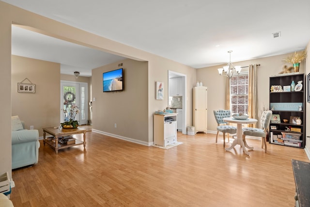 living room with light hardwood / wood-style floors, a wealth of natural light, and a notable chandelier