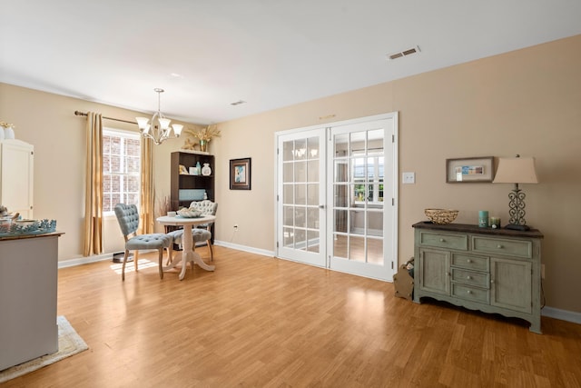 dining room with a healthy amount of sunlight, light hardwood / wood-style floors, and a notable chandelier