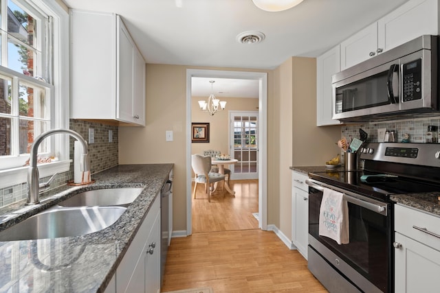 kitchen featuring white cabinetry, sink, stainless steel appliances, light hardwood / wood-style flooring, and a notable chandelier