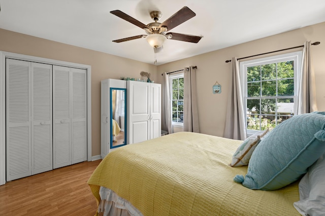 bedroom with multiple windows, ceiling fan, a closet, and light wood-type flooring