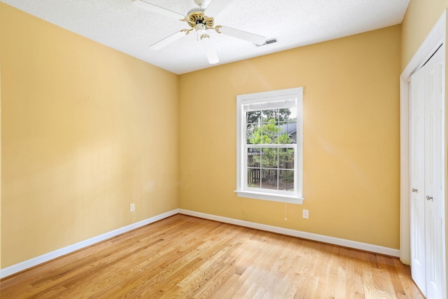 unfurnished bedroom with light wood-type flooring, a textured ceiling, ceiling fan, and a closet