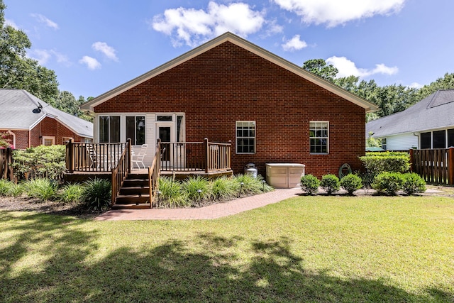 rear view of house featuring a wooden deck and a lawn