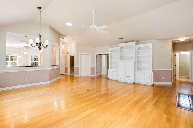 unfurnished bedroom featuring light hardwood / wood-style flooring, vaulted ceiling, an inviting chandelier, and two closets