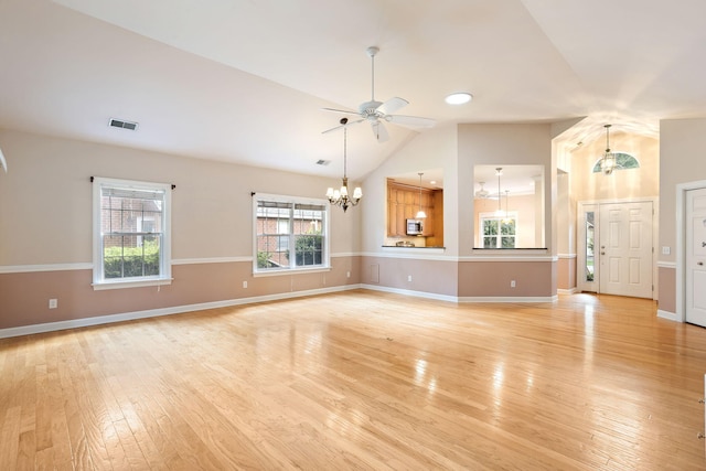 unfurnished living room with vaulted ceiling, ceiling fan with notable chandelier, and light wood-type flooring