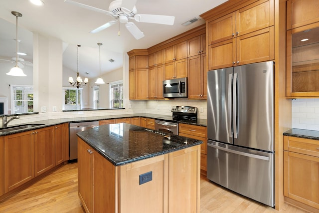 kitchen featuring ceiling fan with notable chandelier, lofted ceiling, kitchen peninsula, and stainless steel appliances