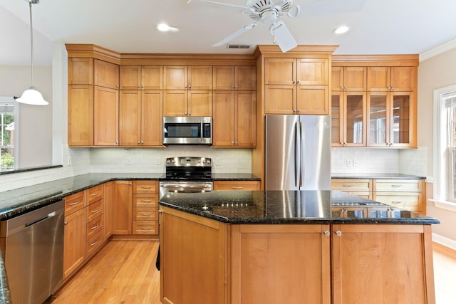 kitchen with decorative light fixtures, light wood-type flooring, stainless steel appliances, dark stone counters, and ceiling fan