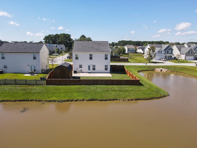 rear view of house with a water view and a lawn