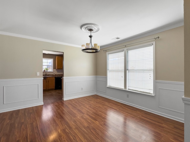 empty room with a notable chandelier, dark hardwood / wood-style floors, and crown molding