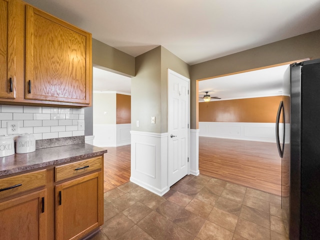 kitchen featuring backsplash, crown molding, hardwood / wood-style flooring, ceiling fan, and stainless steel fridge