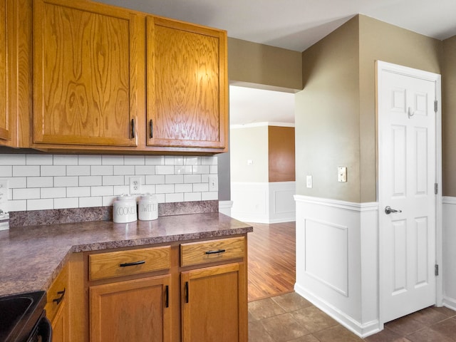 kitchen featuring backsplash, black range, dark wood-type flooring, and ornamental molding