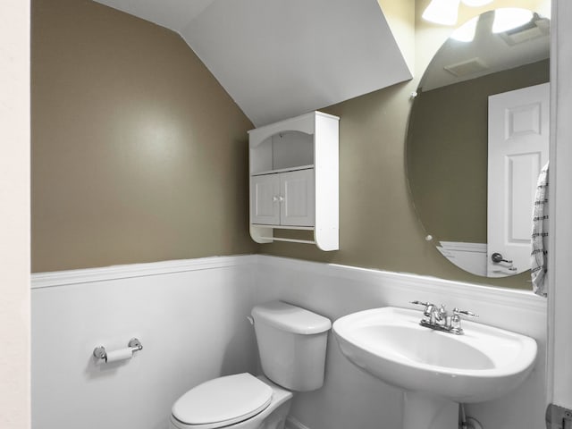 bathroom with toilet, lofted ceiling, and sink