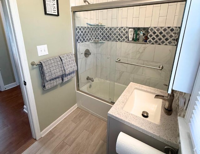 bathroom featuring enclosed tub / shower combo, hardwood / wood-style floors, and vanity