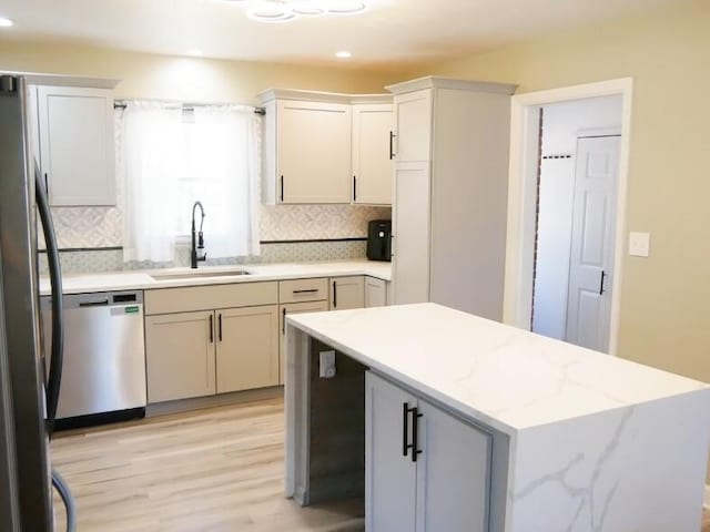 kitchen featuring sink, white cabinetry, light wood-type flooring, stainless steel appliances, and decorative backsplash