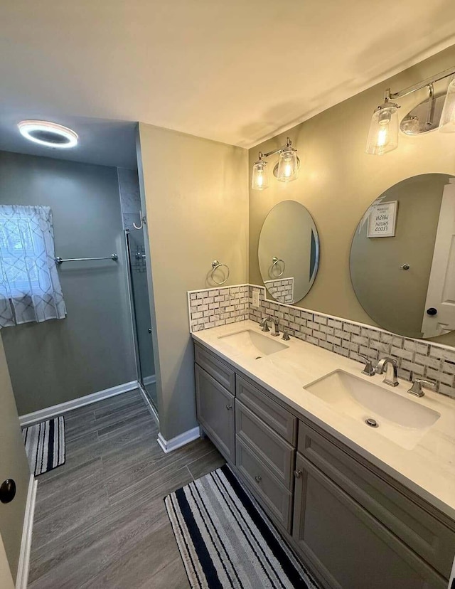 bathroom with tasteful backsplash, vanity, hardwood / wood-style flooring, and a shower with door