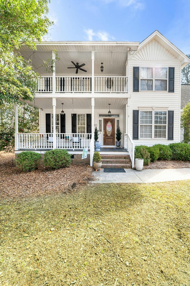 view of front of home with a porch, a front yard, a balcony, and a ceiling fan