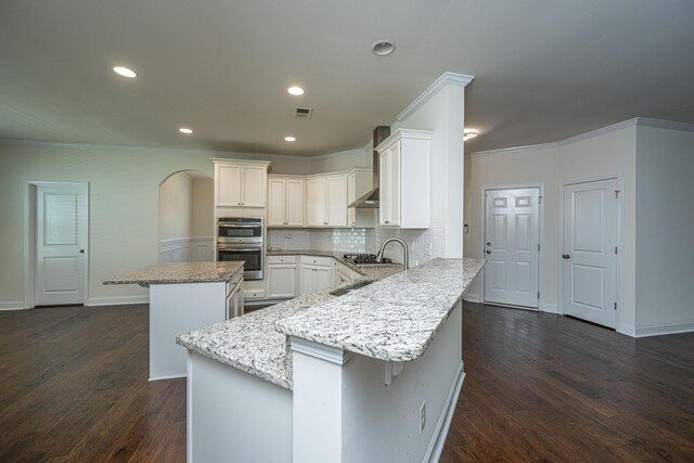 9710 Table Mountain Ln, Ladson, SC 29456 - kitchen featuring ornamental molding, a kitchen island, a peninsula, dark wood-type flooring, and arched walkways