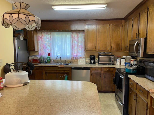 kitchen with ornamental molding, sink, stainless steel appliances, and a textured ceiling