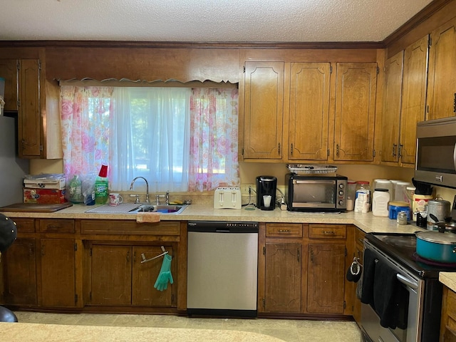 kitchen with a textured ceiling, stainless steel appliances, and sink