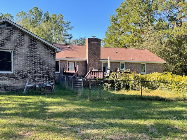 rear view of house featuring a wooden deck and a lawn