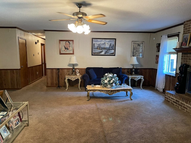 living room featuring carpet flooring, ceiling fan, a fireplace, ornamental molding, and a textured ceiling