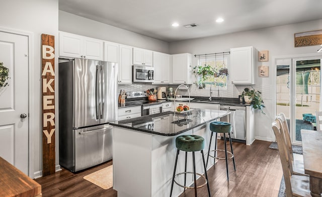 kitchen with a breakfast bar area, dark wood-style floors, a sink, stainless steel appliances, and white cabinets