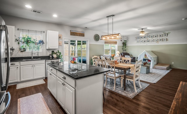 kitchen featuring visible vents, a sink, dark wood-style floors, open floor plan, and a center island