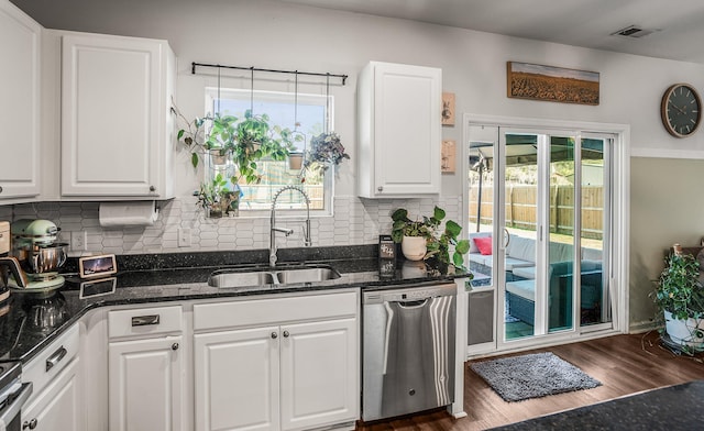 kitchen featuring visible vents, white cabinetry, a sink, dishwasher, and tasteful backsplash