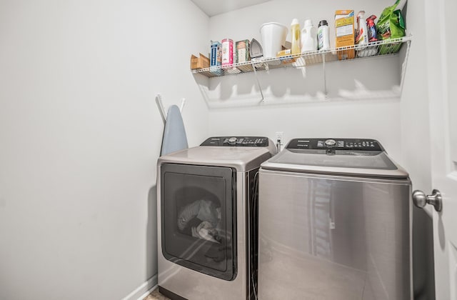 clothes washing area with laundry area, baseboards, and washer and clothes dryer