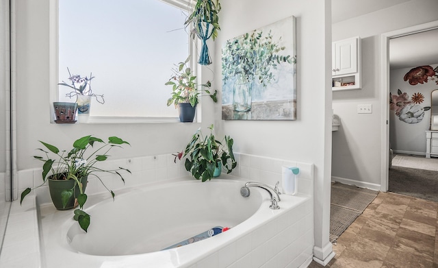 bathroom with a bath and baseboards