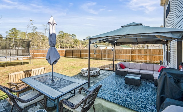 view of patio featuring an outdoor living space with a fire pit, a gazebo, a trampoline, and a fenced backyard