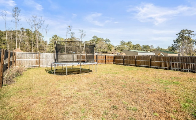 view of yard featuring a trampoline and a fenced backyard