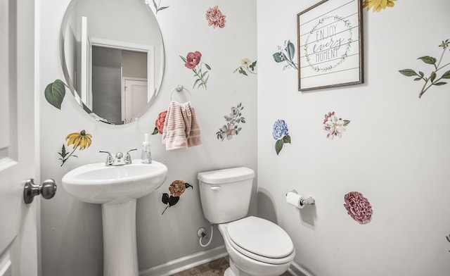 bathroom with toilet, baseboards, and a sink