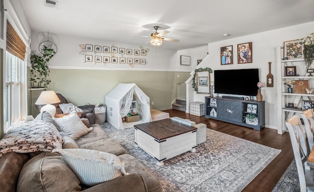 living area with visible vents, a ceiling fan, wood finished floors, baseboards, and stairs