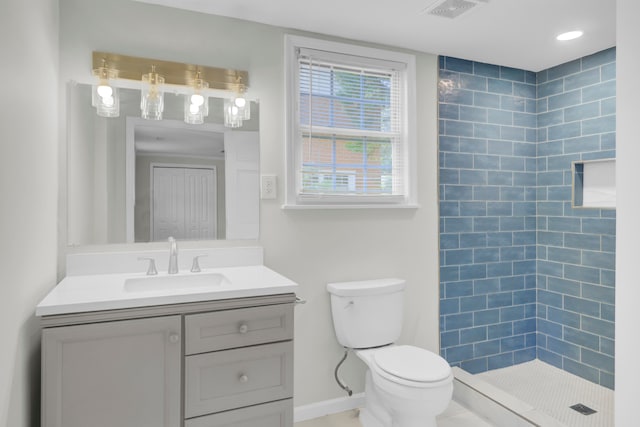 bathroom with vanity, toilet, and a tile shower