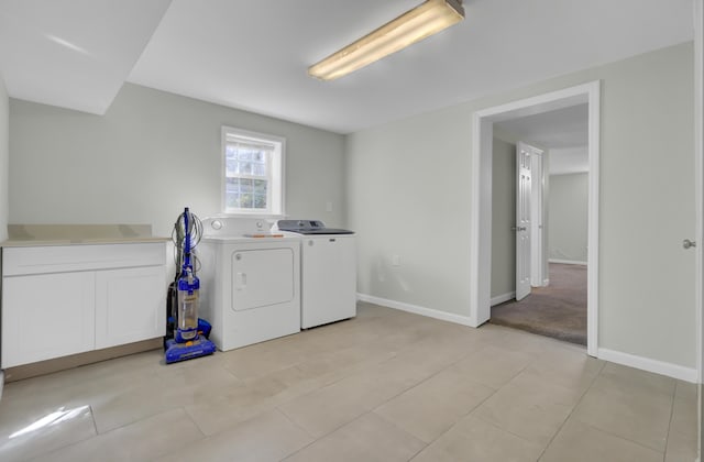 clothes washing area with cabinets, light tile patterned floors, and washing machine and dryer