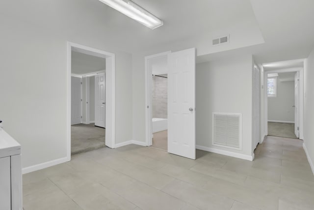 unfurnished bedroom with ensuite bathroom and light tile patterned flooring