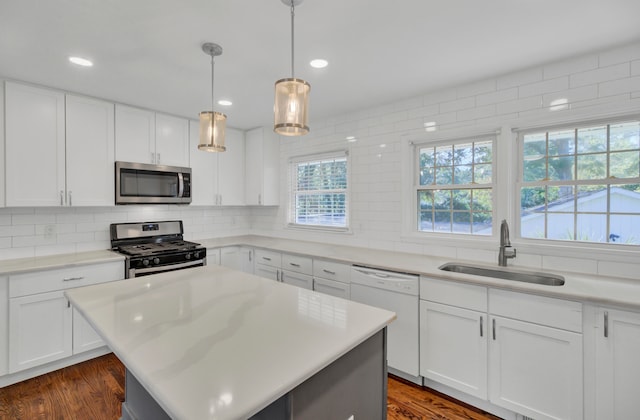 kitchen with appliances with stainless steel finishes, dark hardwood / wood-style floors, white cabinetry, and sink