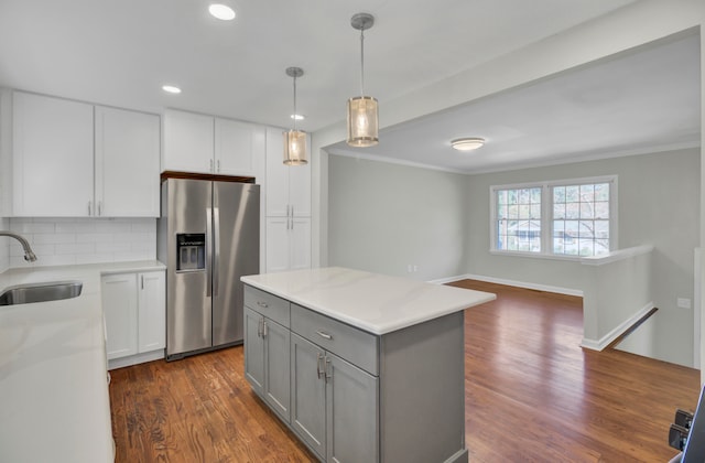 kitchen with dark hardwood / wood-style flooring, sink, pendant lighting, white cabinets, and stainless steel fridge with ice dispenser