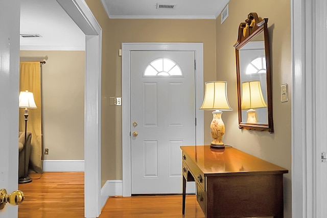 foyer with crown molding and light hardwood / wood-style flooring